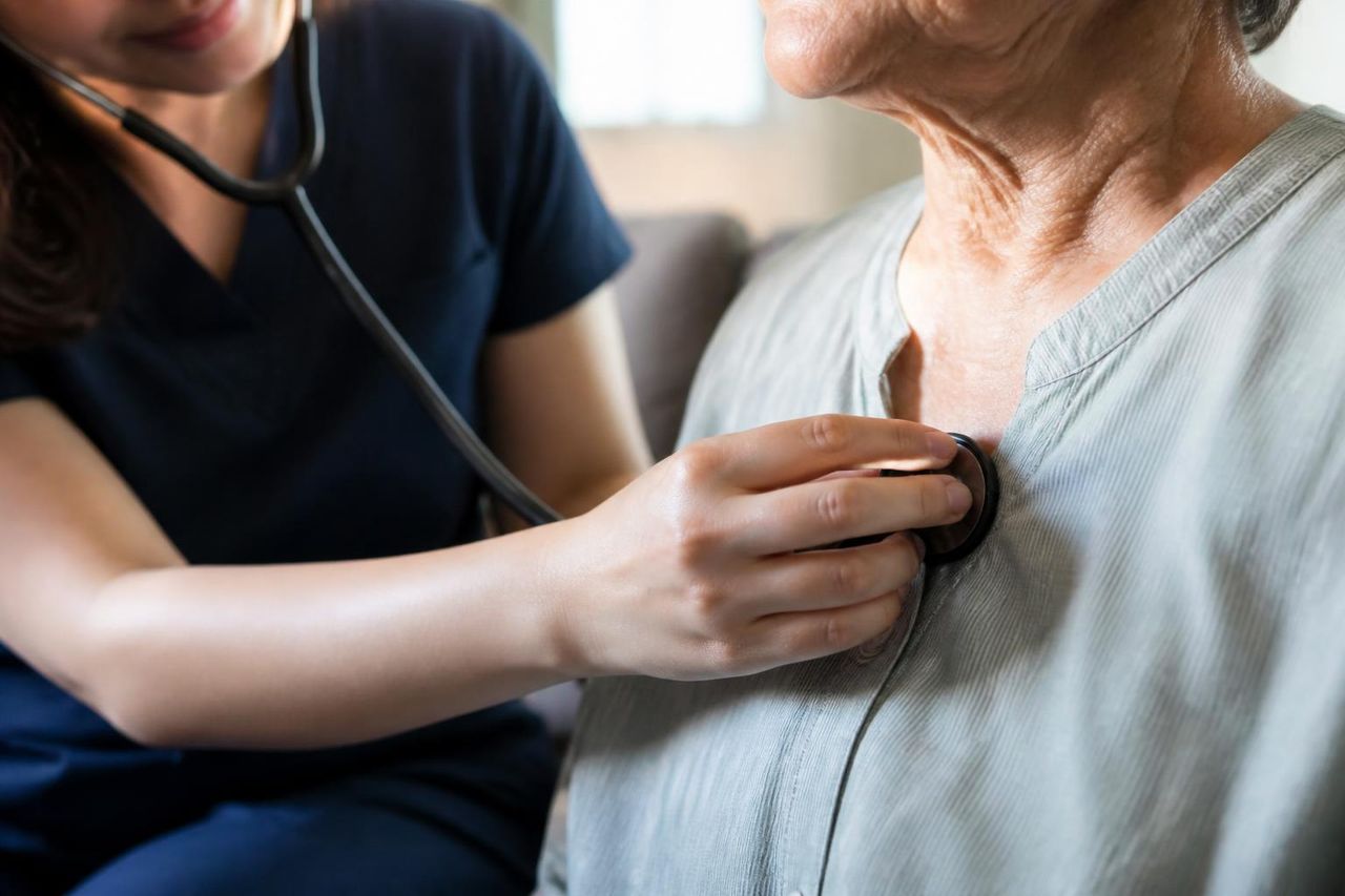 Nurse listening to an older person's chest with a stethoscope during a home visit